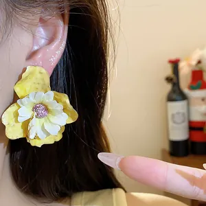 Dettaglio di eleganti orecchini a perno con fiori in tessuto giallo e bianco su modella