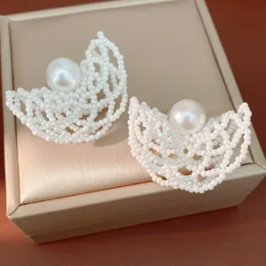 Primo piano di eleganti orecchini fatti a mano con perle su una lussuosa scatola di gioielli.
