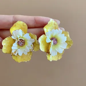 Vista dettagliata di orecchini a fiore in tessuto bianco e olio giallo con ago d'argento