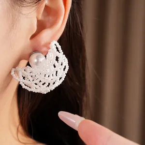 Primo piano di eleganti orecchini circolari in perline bianche con grande perla sull'orecchio