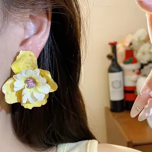 Dettaglio degli orecchini a perno con fiori in tessuto giallo dal design elegante e unico