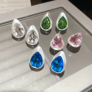 Detailed view of teardrop earrings with brushed metal finish and colorful crystals