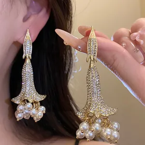 Dettaglio di eleganti orecchini a fiore con strass e nappe di perle.