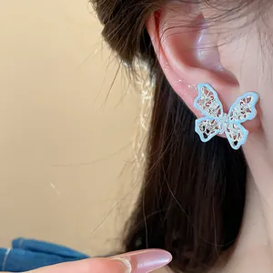 Primo piano di orecchini a farfalla in argento con zircone e ali traforate.