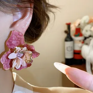 Primo piano elegante di orecchini a lobo a fiore in tessuto rosa con accenti dorati