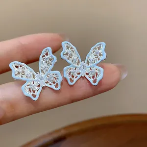Dettaglio macro di orecchini a farfalla in smalto azzurro con pietre di zircone