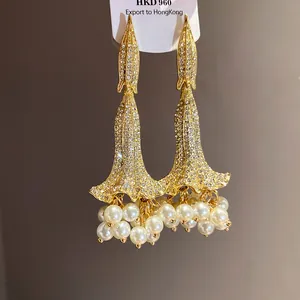 Dettaglio orecchini a fiore dorati stile vintage con perle e cristalli brillanti.