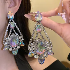Macro close-up of oversized iridescent teardrop chandelier earrings with clear rhinestones