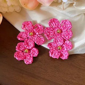 Detail view of handmade pink raffia flower earrings with elegant gold bead centers