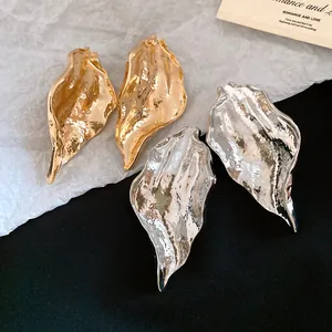 Detailed view of metallic wrinkled leaf-shaped earrings in gold and silver finishes.