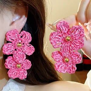 Macro shot of oversized pink woven raffia flower earrings showing detailed texture