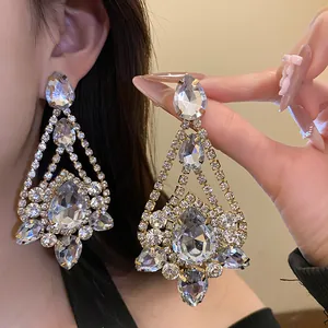 Close-up of elegant rhinestone water drop chandelier earrings worn and held by hand