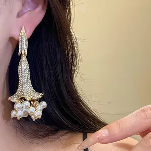 Primo piano di eleganti orecchini vintage dorati con strass e grappoli di perle.