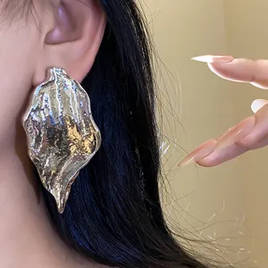 Close-up detail of a stylish oversized silver leaf earring with a hammered texture