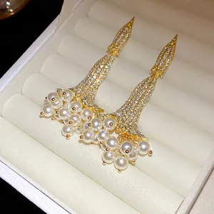 Dettaglio di orecchini vintage in oro con diamanti scintillanti e perle in scatola.