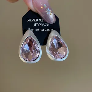 Close-up of vintage teardrop earrings with pink faceted crystals and matte finish