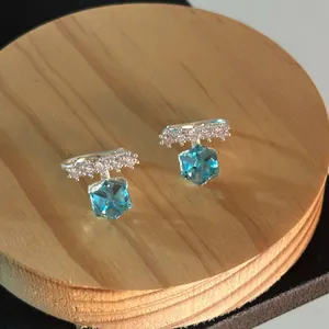 Detailed macro view of sparkling silver ear cuffs with blue geometric zircon stones.