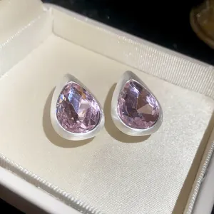 Close-up of vintage teardrop earrings with brushed silver finish and purple stones
