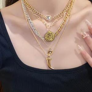 Detailed view of layered vintage gold necklaces with coin, horn, and gem pendants