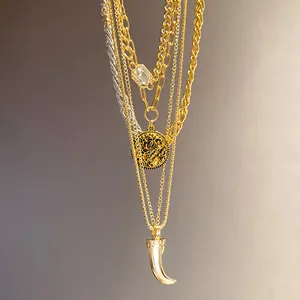 Macro shot of layered gold necklace featuring crystal, vintage coin, and horn pendants
