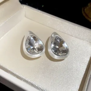 Close-up of vintage waterdrop stud earrings with brushed silver finish and faceted crystals