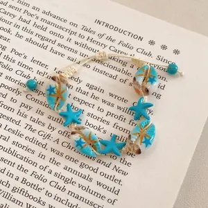 Detailed macro view of a handmade blue shell and starfish beaded bracelet on a book