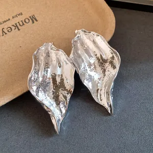 Macro detail of silver crumpled leaf earrings showing unique metallic texture