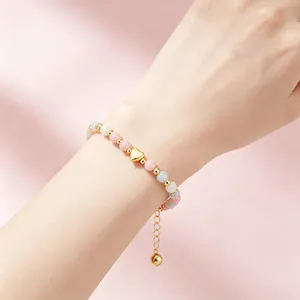 Détail rapproché d'un bracelet en quartz rose et aigue-marine avec pendentif cœur doré