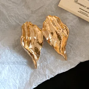 Macro shot of the intricate wrinkled texture on these gold-tone leaf-shaped earrings.