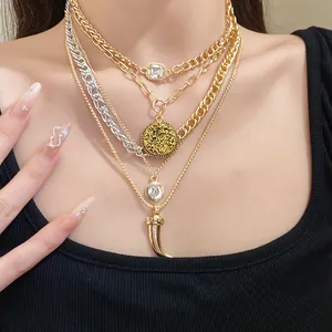 Close-up of layered vintage gold and silver necklaces with horn and disk pendants.