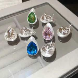 Detail view of vintage teardrop stud earrings with brushed metal finish and colorful stones