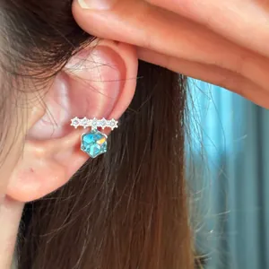 Close-up of elegant ear cuff featuring blue hexagonal zircon and sparkling stones