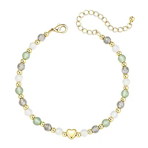 Détail d'un pendentif cœur doré et de perles en pierre naturelle sur un bracelet