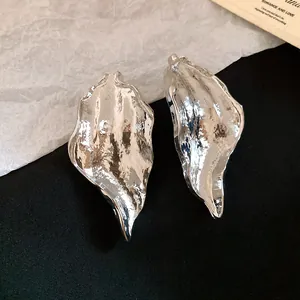 Detailed close-up of silver-toned wrinkled leaf earrings with textured hammered finish