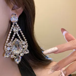Detailed close-up view of sparkling silver needle rhinestone teardrop earrings on a model
