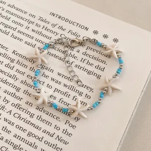 Detailed macro view of a stylish blue and white starfish beaded bracelet resting on a vintage book