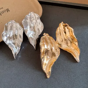 Detail shot of textured gold and silver leaf earrings with wrinkled metallic finish