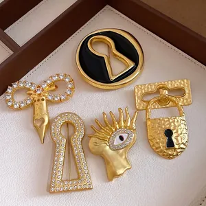 Vintage style keyhole and eye motif gold brooches set with zircons
