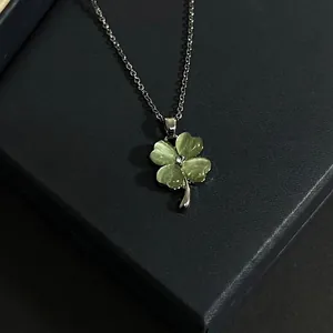 Close-up of a four-leaf clover necklace with green cat's eye petals and rhinestone center.