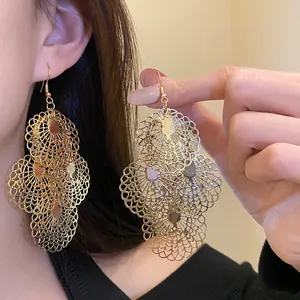 Macro view of elegant gold metal circular filigree earrings with intricate lace patterns.