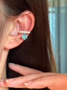 Detailed macro view of an elegant zircon ear cuff with hexagonal blue crystal on ear