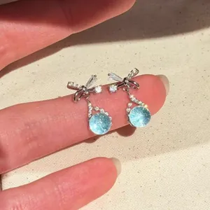 Macro detail of elegant bowknot earrings with sparkling light blue zircon crystal drops.