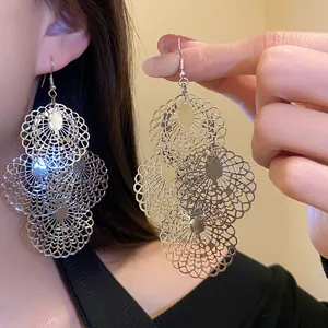 Macro view of large silver filigree layered circular hollowed-out drop earrings for women