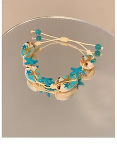 Close-up of beach-style bracelet with blue starfish and white shells on mirror
