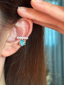 Detailed view of a sparkling blue zircon ear cuff worn on an elegant minimalist model's ear