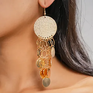 Close-up of golden round sequin tassel drop earrings showing refined metallic texture
