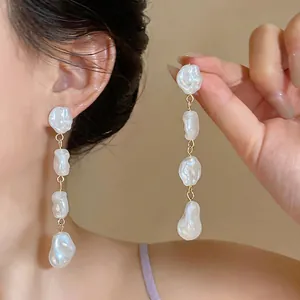 Primo piano di orecchini a nappa lunga con perle barocche sull'orecchio della modella