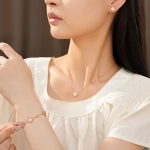 Modelo asiática luciendo un conjunto de joyas de flores rosas con collar y pulsera.