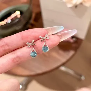 Detailed view of elegant blue zircon drop earrings with a bow-knot design in silver