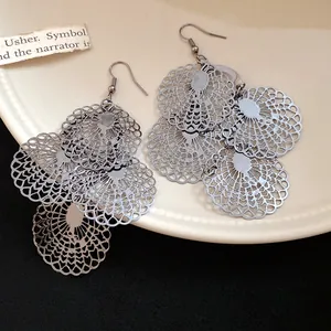 Detail view of intricate silver-tone metal hollow lace pattern dangling earrings